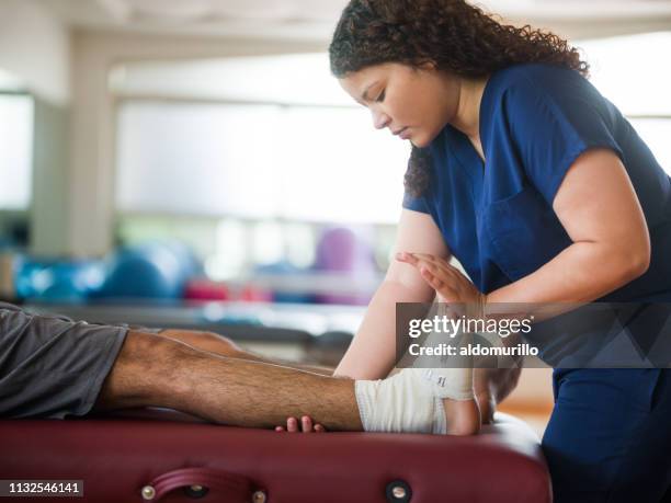 患者の脚と足を保持する作業療法士 - injured ストックフォトと画像