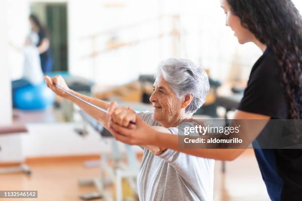 occupational therapist helping patient to raise arms - old trying to look young stock pictures, royalty-free photos & images