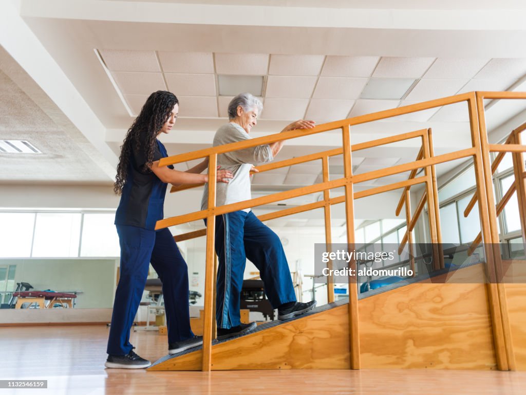 Senior vrouw gaat een oprit tijdens fysiotherapeut