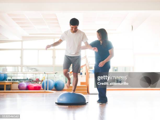 mannelijke fysieke rehab patiënt staande op bosu bal - kinesist stockfoto's en -beelden