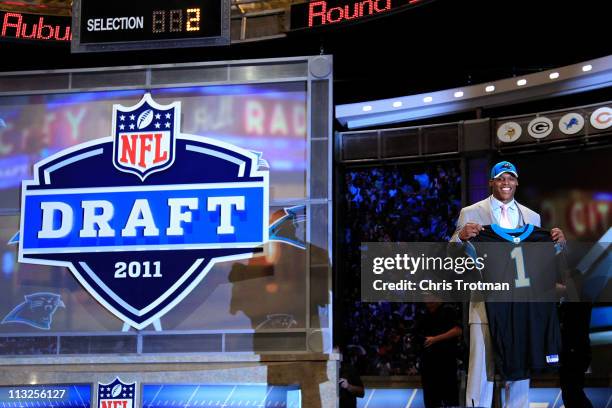 Cam Newton, #1 overall pick by the Carolina Panthers holds up a jersey on stage after he was picked during the 2011 NFL Draft at Radio City Music...