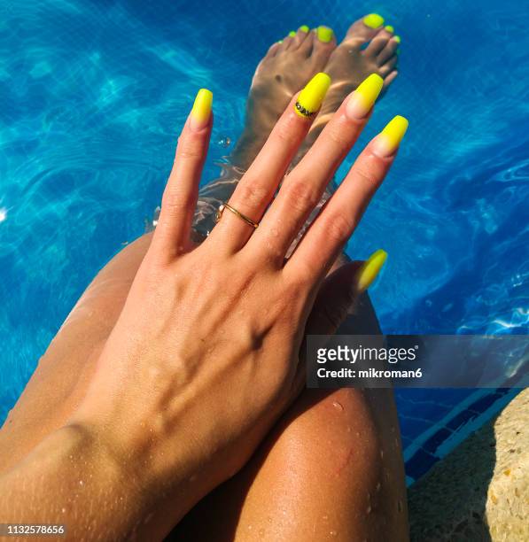 close-up of woman fingers with nail art manicure with neon green colour in a swimming pool - get manicure stock-fotos und bilder