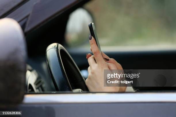 woman driving car distracted by her mobile phone - mobile phone in hand driving stock pictures, royalty-free photos & images
