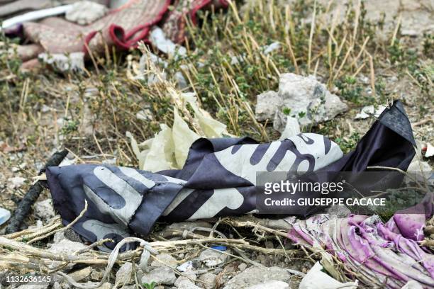 This picture taken on March 24, 2019 shows a discarded Islamic State group flag lying on the ground in the village of Baghouz in Syria's eastern Deir...
