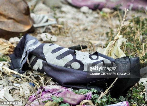 This picture taken on March 24, 2019 shows a discarded Islamic State group flag lying on the ground in the village of Baghouz in Syria's eastern Deir...