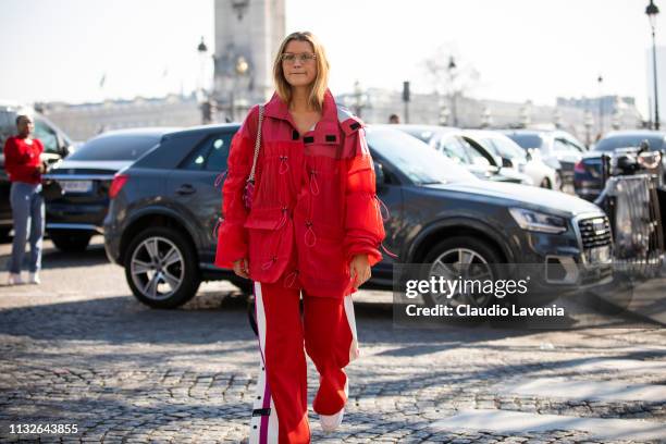 Guest, wearing a decorated red jacket, red sporty pants, white sneakers and pink bag, is seen outside Unravel Project on Day 3 Paris Fashion Week...