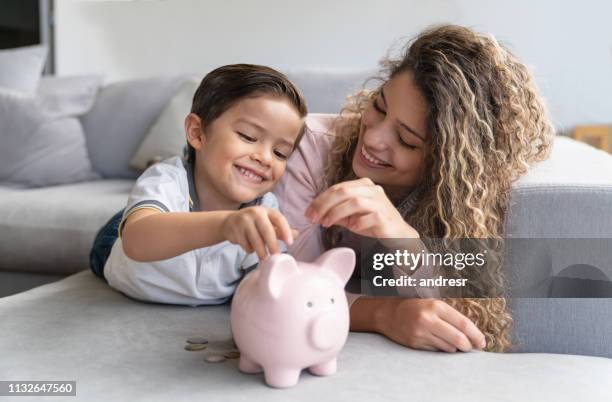 glückliche mutter und sohn sparen geld in einem sparschwein - sparsamkeit stock-fotos und bilder