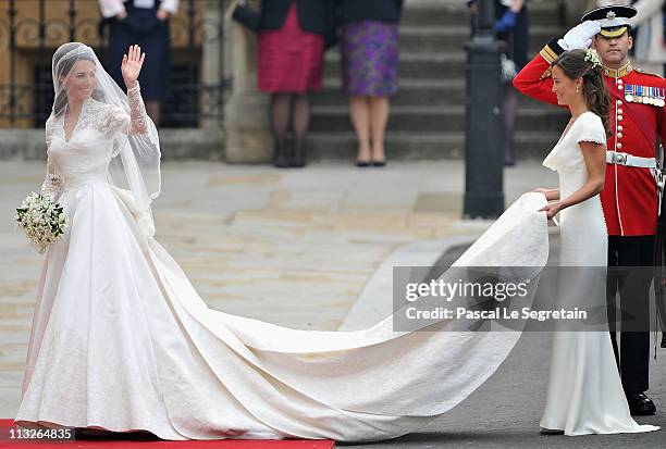 Catherine Middleton waves to the crowds as her sister and Maid of Honour Pippa Middleton holds her dress before walking in to the Abbey to attend the...