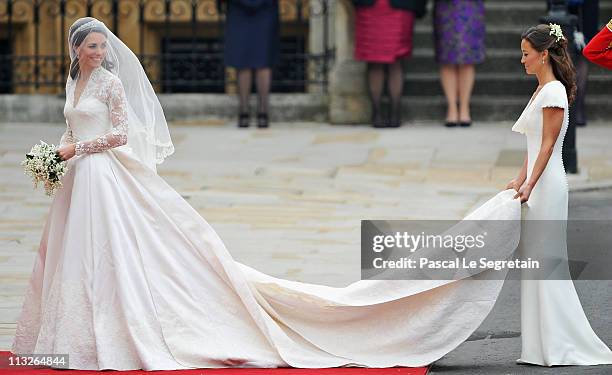 Catherine Middleton waves to the crowds as her sister and Maid of Honour Pippa Middleton holds her dress before walking in to the Abbey to attend the...