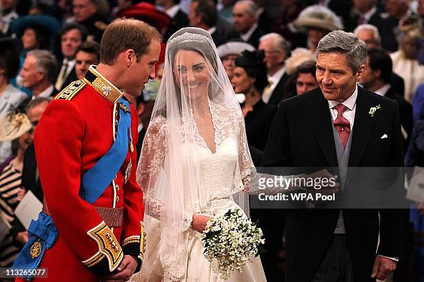 Prince William speaks to his bride, Catherine Middleton as she holds the hand of her father Michael Middleton at Westminster Abbey on April 29, 2011...