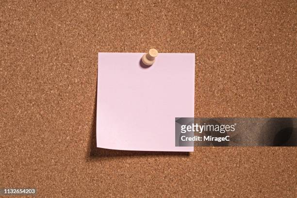 pink colored note paper on cork board - chincheta fotografías e imágenes de stock