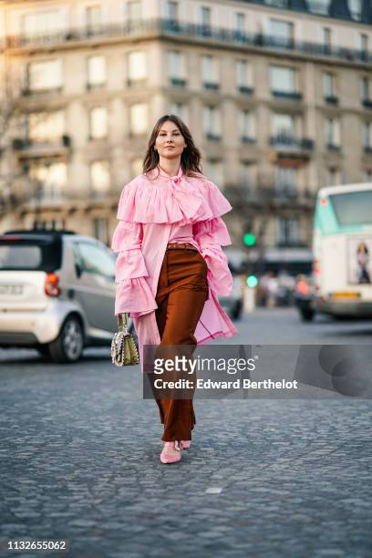 Angelica Ardasheva wears a pink ruffled long shirt, a bag with embroidery, brown flared pants, pink shoes, outside Rochas, during Paris Fashion Week...
