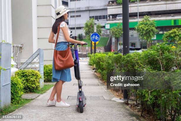 trendy woman, beautiful chinese tourist riding electric scooter in modern city - girl riding scooter stock pictures, royalty-free photos & images