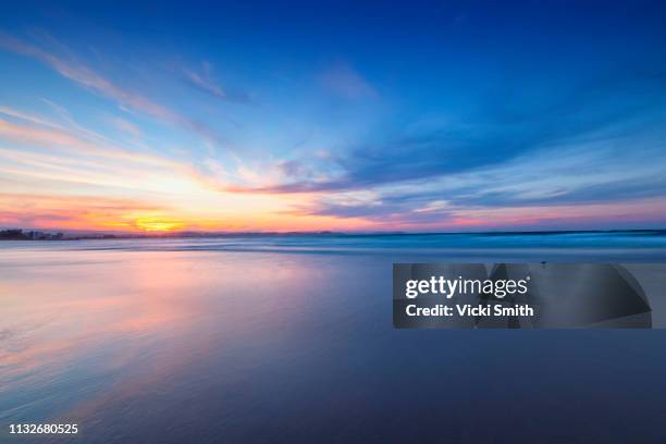 beautiful yellow and blue sky sunrise over the ocean - australia summer reflection stock-fotos und bilder