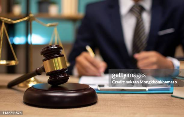judge gavel with justice lawyers having team meeting at law firm in background - studio legale foto e immagini stock