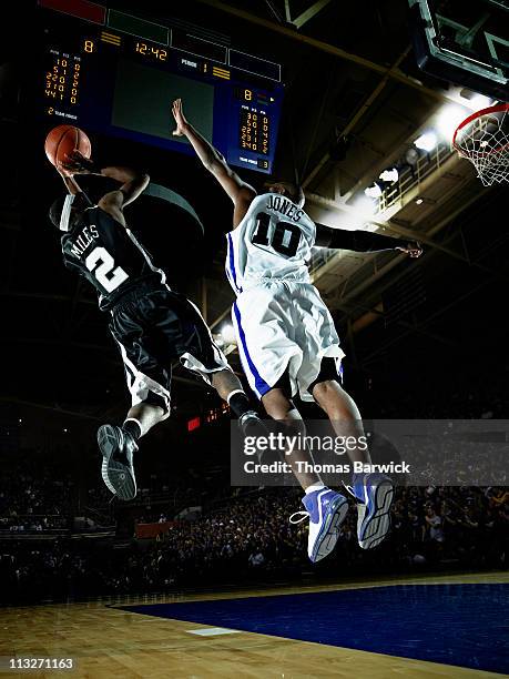 basketball player shooting over defender in arena - basketball verteidiger stock-fotos und bilder