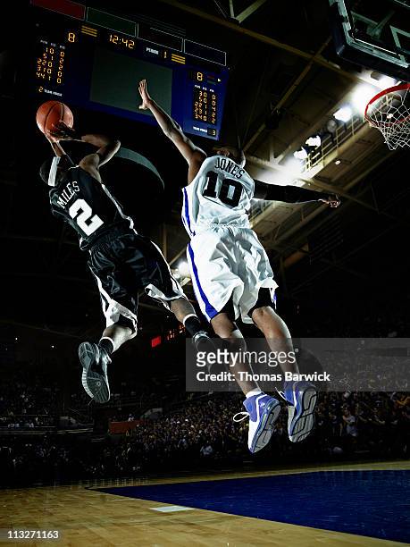 basketball player shooting over defender in arena - basketteur photos et images de collection