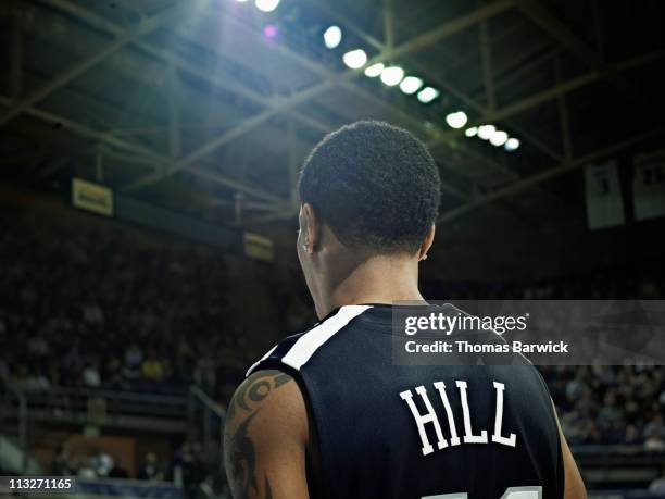 basketball player looking out at crowded arena - uniforme di basket foto e immagini stock