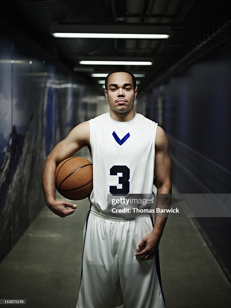 Basketball player standing in hallway of arena