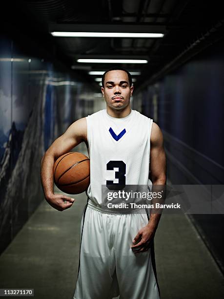 basketball player standing in hallway of arena - basketbaltenue stockfoto's en -beelden