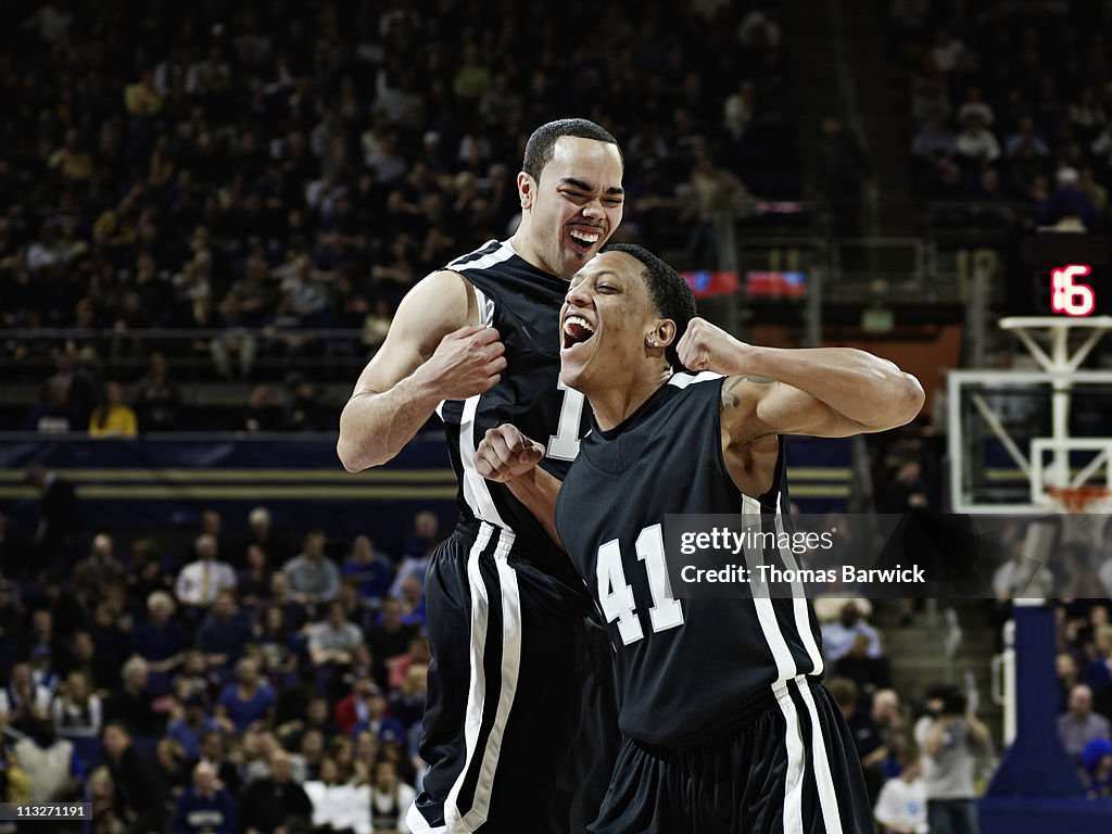 Basketball players in crowded arena celebrating