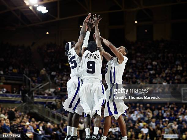 three basketball players celebrating in arena - basketball trikot stock-fotos und bilder
