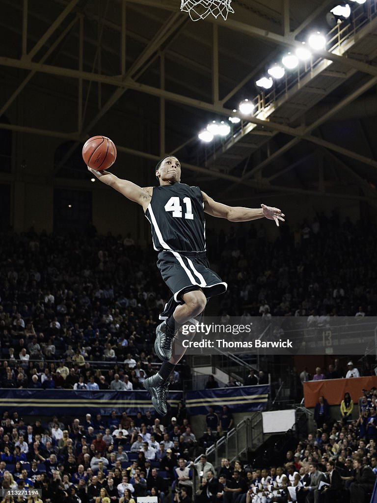 Basketball player preparing to dunk ball in arena