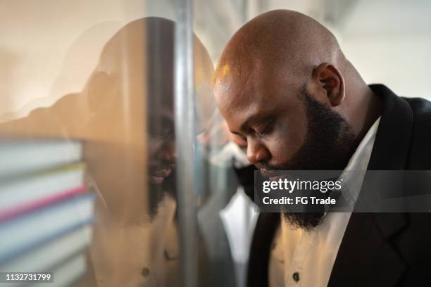 frustrated afro man feeling loser standing near the window - covid despair stock pictures, royalty-free photos & images