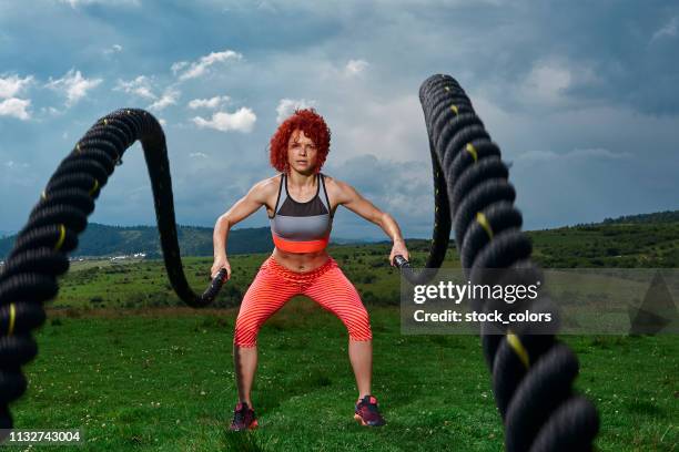 active and powerful sportive woman - battle rope stock pictures, royalty-free photos & images