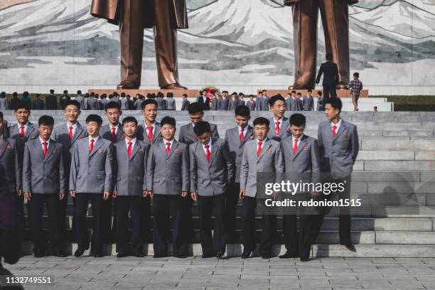 marching solemnly to gigantic bronze statues in pyongyang - north korea people stock pictures, royalty-free photos & images