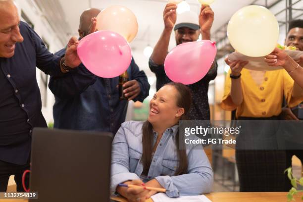 medewerkers het voorbereiden van een verjaardag verrassing voor hun speciale behoeften collega vrouw - jubileum werk stockfoto's en -beelden