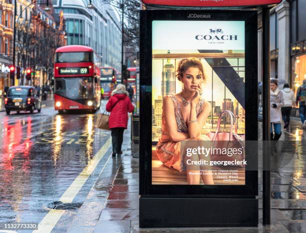 bus stop advertisement on rainy london street - london fashion stock pictures, royalty-free photos & images
