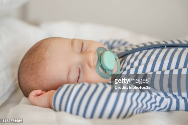 baby sleeping on white quilt - pacifier stock pictures, royalty-free photos & images