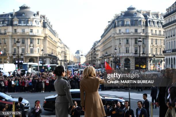 French president's wife Brigitte Macron and Chinese president's wife Peng Liyuan wave to a crowd as they visit the Palais Garnier opera house in...