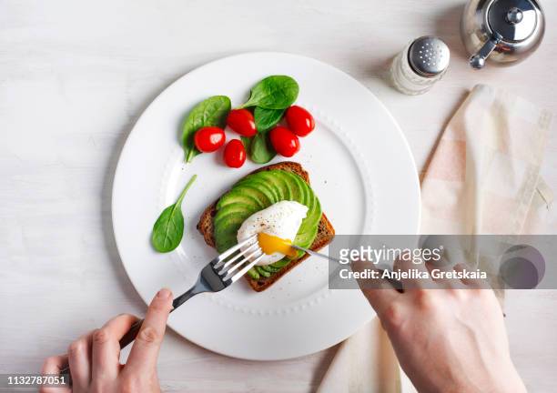 avocado sandwich with poached egg. sliced avocado and egg on toasted bread for healthy breakfast - escalfado fotografías e imágenes de stock