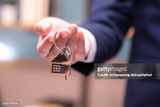 home concept,businessmen holding home keys - home key stockfoto's en -beelden