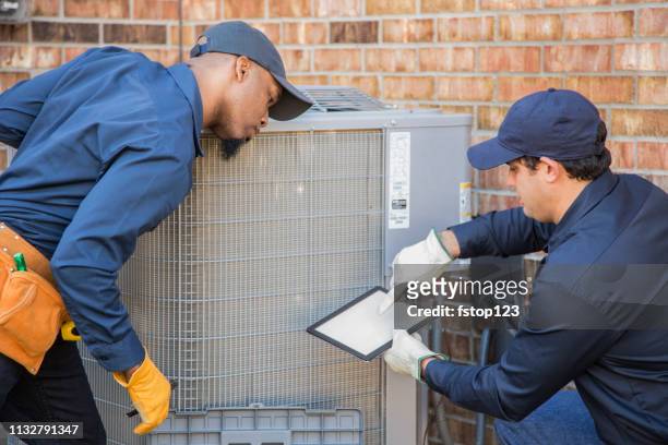 multi-ethnic team of blue collar air conditioner repairmen at work. - repairing stock pictures, royalty-free photos & images