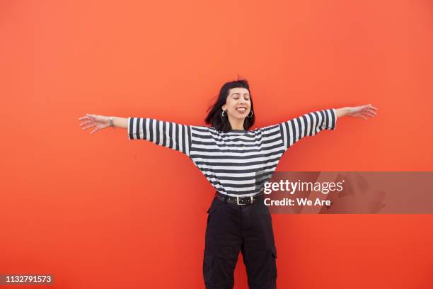 woman in striped top with arms outstretched, smiling. - lucky stock-fotos und bilder