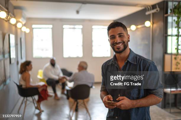 latin male portrait using mobile at work studio - business man mobile phone stock pictures, royalty-free photos & images
