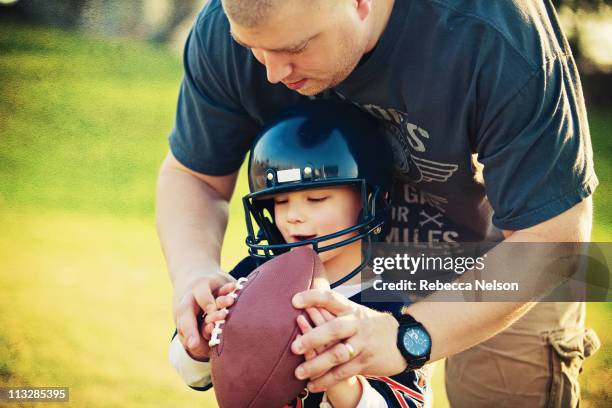 father teaching young son how to hold a football - american football family stock pictures, royalty-free photos & images