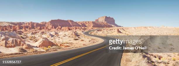 winding empty road through arid desert landscape panoramic - wonderlust stock-fotos und bilder