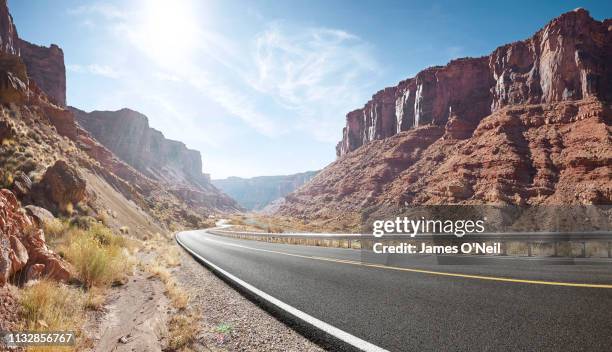 empty curved road in sandstone cliff valley - moab utah stockfoto's en -beelden