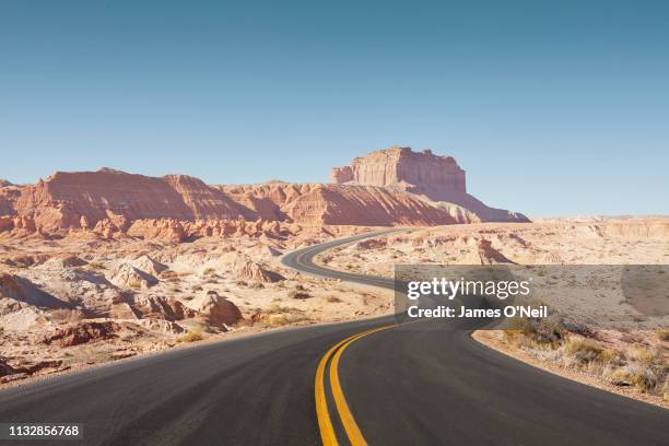 winding empty road through arid desert landscape - amerikanische kontinente und regionen stock-fotos und bilder