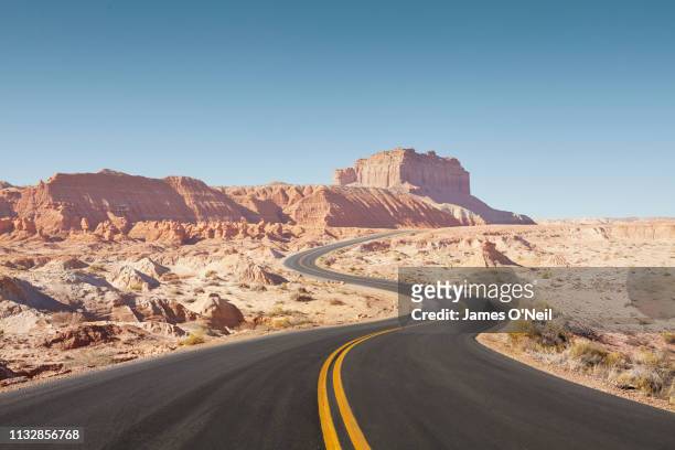 winding empty road through arid desert landscape - ドライブ旅行 ストックフォトと画像