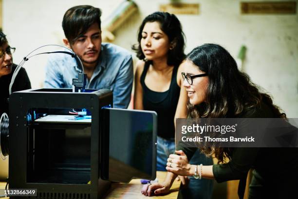 smiling female engineer watching prototype being printed on 3d printer in workshop - プロトタイプ ストックフォトと画像