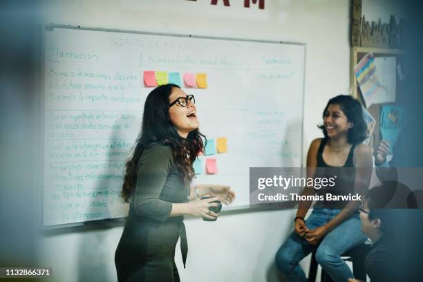 laughing female engineer leading project discussion with coworkers in workshop - fun at work stockfoto's en -beelden