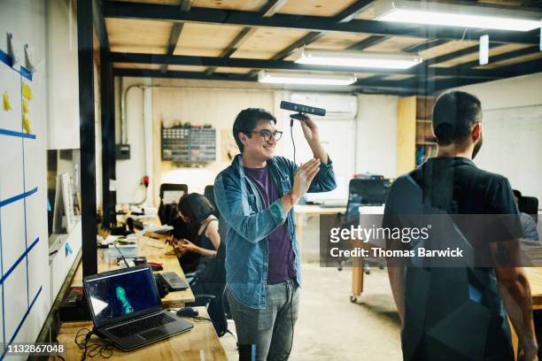 smiling engineer creating 3d scan of coworker in design studio - computer work life balance stock-fotos und bilder