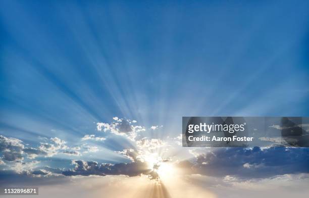 sunset behind clouds - sunlight stock-fotos und bilder