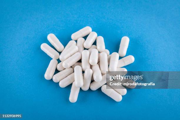 close up of health supplement pills on a blue background - medicamento stock pictures, royalty-free photos & images