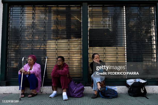 Patients on dialysis treatment wait outside a closed clinic during a power outage in Caracas on March 26, 2019. - A new blackout swept across...